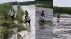 Helpless father carries son on his shoulders across a swollen river
